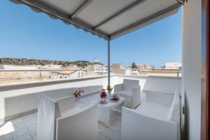 a balcony with white chairs and a view of the city at La Dimora del Passante in San Vito lo Capo