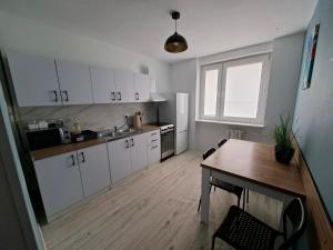 a kitchen with white cabinets and a table and a window at Apartament w Centrum III in Ustka