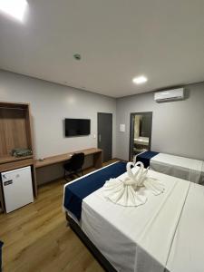 a hotel room with two beds and a flat screen tv at Hotel Bonfim in Silvânia