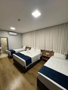 a hotel room with two beds and a window at Hotel Bonfim in Silvânia
