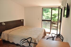 a bedroom with a bed and a table and a window at Las Artes Lodge in Mina Clavero