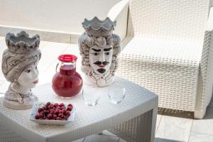 a table with vases and a statue and a bowl of berries at La Dimora del Passante in San Vito lo Capo