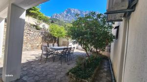 a patio with a table and chairs and a mountain at Studios Dolček in Krvavica