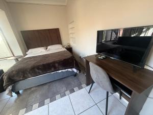 a bedroom with a bed and a desk with a flat screen tv at Suite Dreams Cute Studio Flat in Panorama