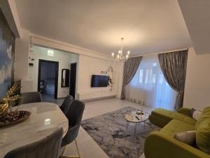 a living room with a table and a green couch at DeLux Apartment -Militari Residence Rosu Chiajna in Dudu