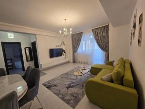 a living room with a green couch and a table at DeLux Apartment -Militari Residence Rosu Chiajna in Dudu +9 photos