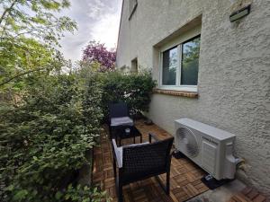 a patio with a heater and two chairs and a window at Obsidian Suite Love Room in Triel-sur-Seine
