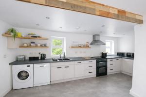 a kitchen with white cabinets and a washer and dryer at Swallows Rest Cottage - 3 Bedrooms - Nr Looe in Looe