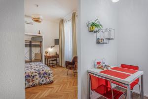 une chambre avec un lit et une table avec des chaises rouges dans l'établissement PARMA EXPRESS Traveller's Lodging front Station FS PARKING & Bicycle Storage, à Parme