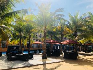 a resort with palm trees and tables and umbrellas at A cozy modern design Unit 6425 in Cebu City