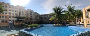 a large swimming pool with palm trees and buildings at A cozy modern design Unit 6425 in Cebu City +4 photos