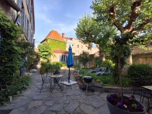 a patio with a table and a blue umbrella at Villa Toscane in Saint-Germain-Lembron