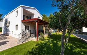 a white house with a tree in front of it at Apartman in Seline