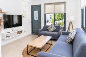 a living room with two blue couches and a tv at Julipapas Gardens in Paphos