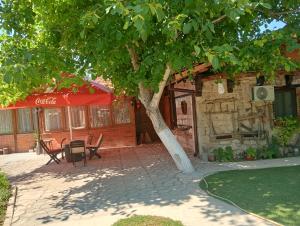a tree in front of a building with a table and chairs at Мехса in Svetoslav