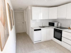 a white kitchen with a sink and a microwave at D&C Norway in Kristiansand