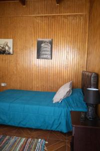 a bedroom with a bed with a blue sheet and a wooden wall at Noface 2 in El Cerrillo