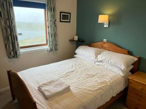 a bedroom with a bed with white sheets and a window at The Westings in Tingwall