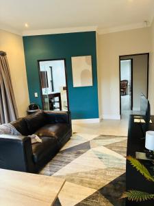 a living room with a leather couch and a blue wall at The Folkestone Guest House in Gqeberha