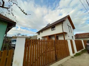 a white house behind a wooden fence at Mi casa su casa in Lăzarea