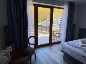 a bedroom with a bed and a view of a balcony at Pensjonat Nad Rzeką in Wisła