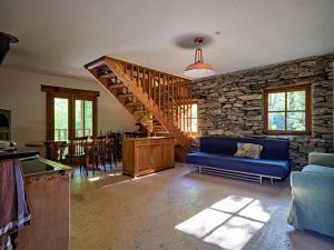 a living room with a blue couch and a stone wall at Hostelleria in Linescio