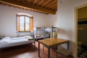 a room with two bunk beds and a table at Student's Hostel Gowett in Campiglia Marittima