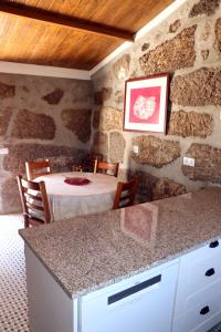 a kitchen with a table in a room with a stone wall at Casa do Maninho in Amarante