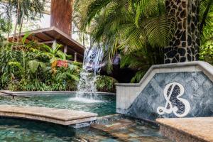 a swimming pool with a fountain in front of a giraffe at Baldi Hot Springs Hotel & Spa in Fortuna