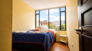 a bedroom with a bed and a large window at Apartamentos CasaMJ Tunja Confort y Parqueadero in Tunja