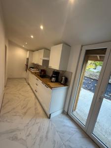 a kitchen with white cabinets and a large window at La Clef des Champs in Mecquignies