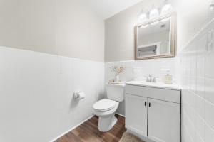 a white bathroom with a toilet and a mirror at GSU Getaway 4BR3BA spacious pet friendly in Statesboro +27 photos