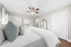 a bedroom with a white bed with a ceiling fan at GSU Getaway 4BR3BA spacious pet friendly in Statesboro