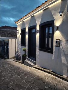 a white house with a black door on a street at CONSTA Luxury House in Mantamádos