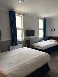two beds in a room with blue curtains at Adelphi Guest House in Douglas