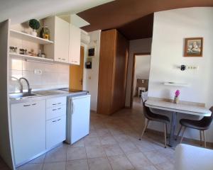 a kitchen with white cabinets and a table with chairs at Guesthouse Anita in Kotor +9 photos