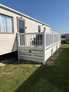 a white rv with a porch and a deck at Sunrise in Selsey