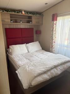 a large bed with a red headboard in a bedroom at Sunrise in Selsey