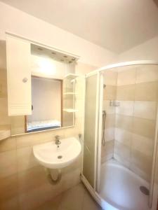 a white bathroom with a sink and a shower at Noclegi Lux Nysa in Nysa