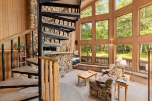 a living room with a spiral staircase and large windows at Causeway On Gull - 2 Bedroom in Nisswa