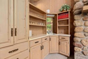 a kitchen with white cabinets and a stone wall at Causeway On Gull - 2 Bedroom in Nisswa