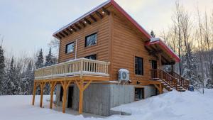 a log cabin with a deck in the snow at Domaine Valga in Saint-Gabriel