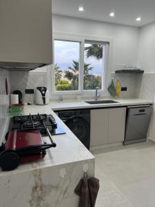 a white kitchen with a stove and a window at Apparemment Martil Sofia bay in Martil