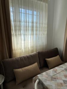 a couch in a living room with a window at HORIZONT Rooms in Lukovë