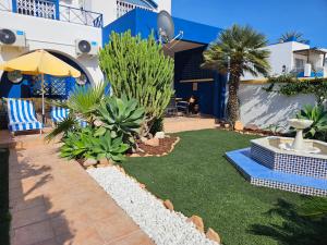 a backyard with a lawn with chairs and an umbrella at El sueño de Rocío in Roquetas de Mar