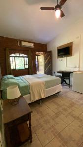 a bedroom with a bed and a table and a desk at Pousada Cantarel in Maricá