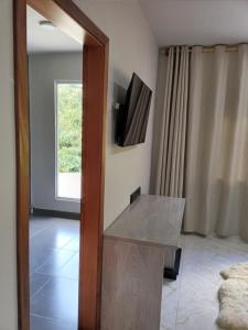 a room with a mirror and a tv on a wall at Pousada Casa Terra de Pinheiros in Santo Antônio do Pinhal