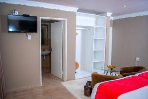 a living room with a bed and a tv on a wall at Guesthouse Gabby in Klerksdorp