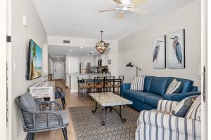 a living room with a blue couch and a table at Majestic Resort! Newly Updated Beachfront 3BR Condo in Panama City Beach