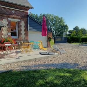 a patio with a table and chairs and an umbrella at L'ancienne forge 3 chambres d'hôtes à l'étage la forge , l'enclume et le marteau in Louvetot